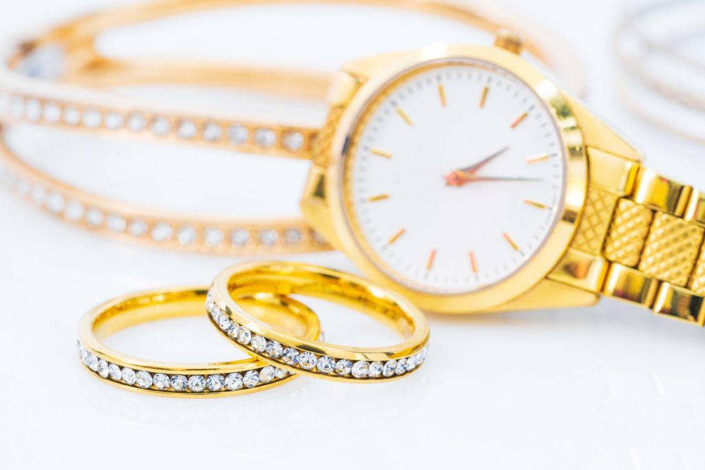 Luxury gold ring and lady gold watch on white_